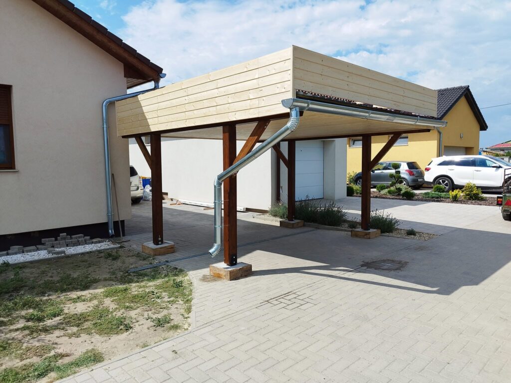 Házhoz csatlakozó fa kocsibeálló sötét oszlopokkal